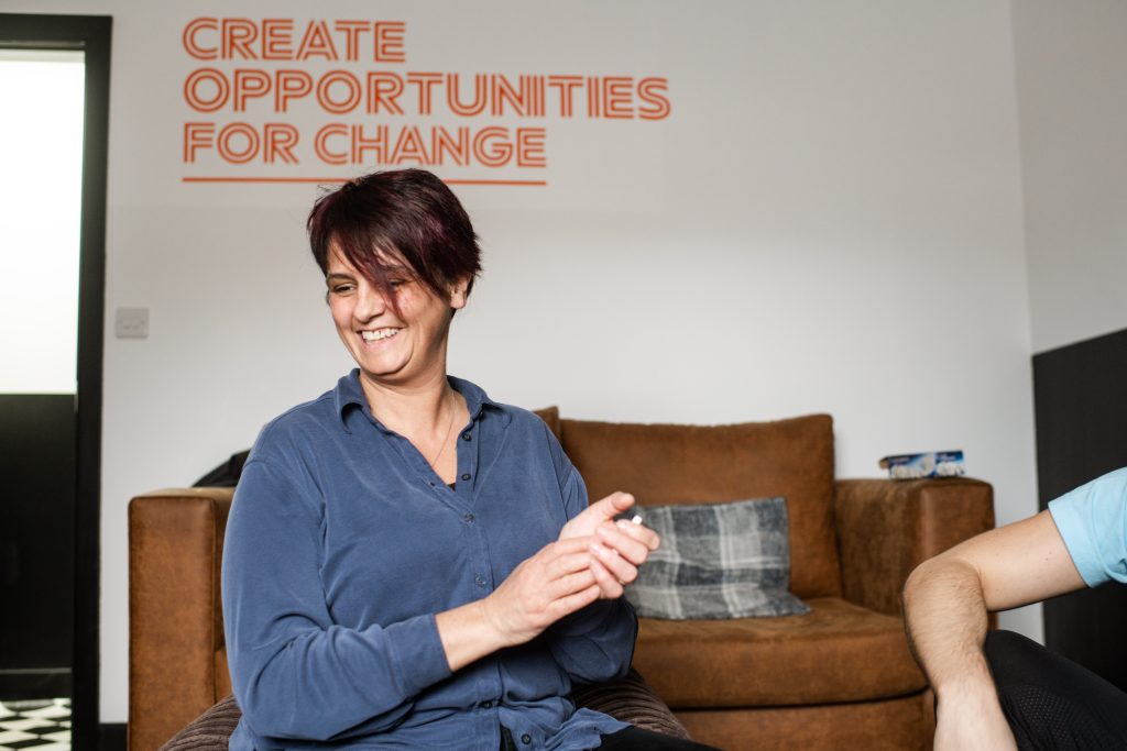 Woman sits on coach with words behind her "Creating Opportunities for Change"