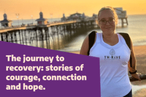 A person wearing glasses and a white tank top with the logo "THRIVE" stands near a railing with a pier and ocean in the background during sunset. The image includes text on a purple background that reads, "The journey to recovery: stories of courage, connection and hope."