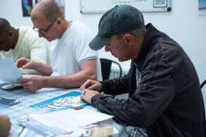 A man wears a hat and is journalling